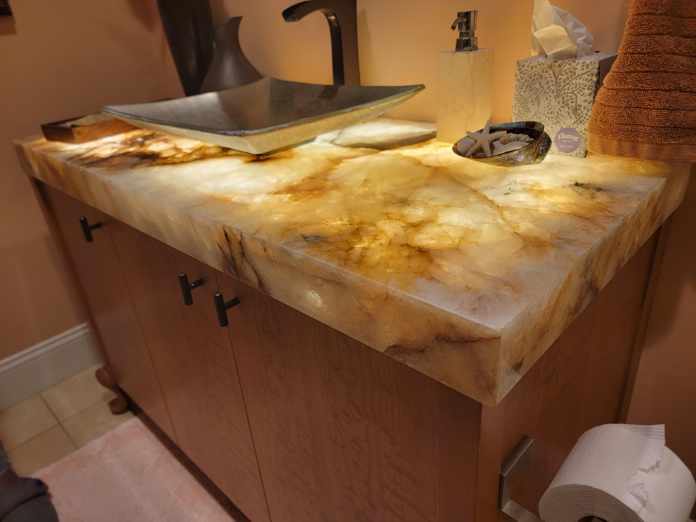 Luxury backlit onyx bathroom vanity countertop with vessel sink and matte black faucet — custom stone fabrication