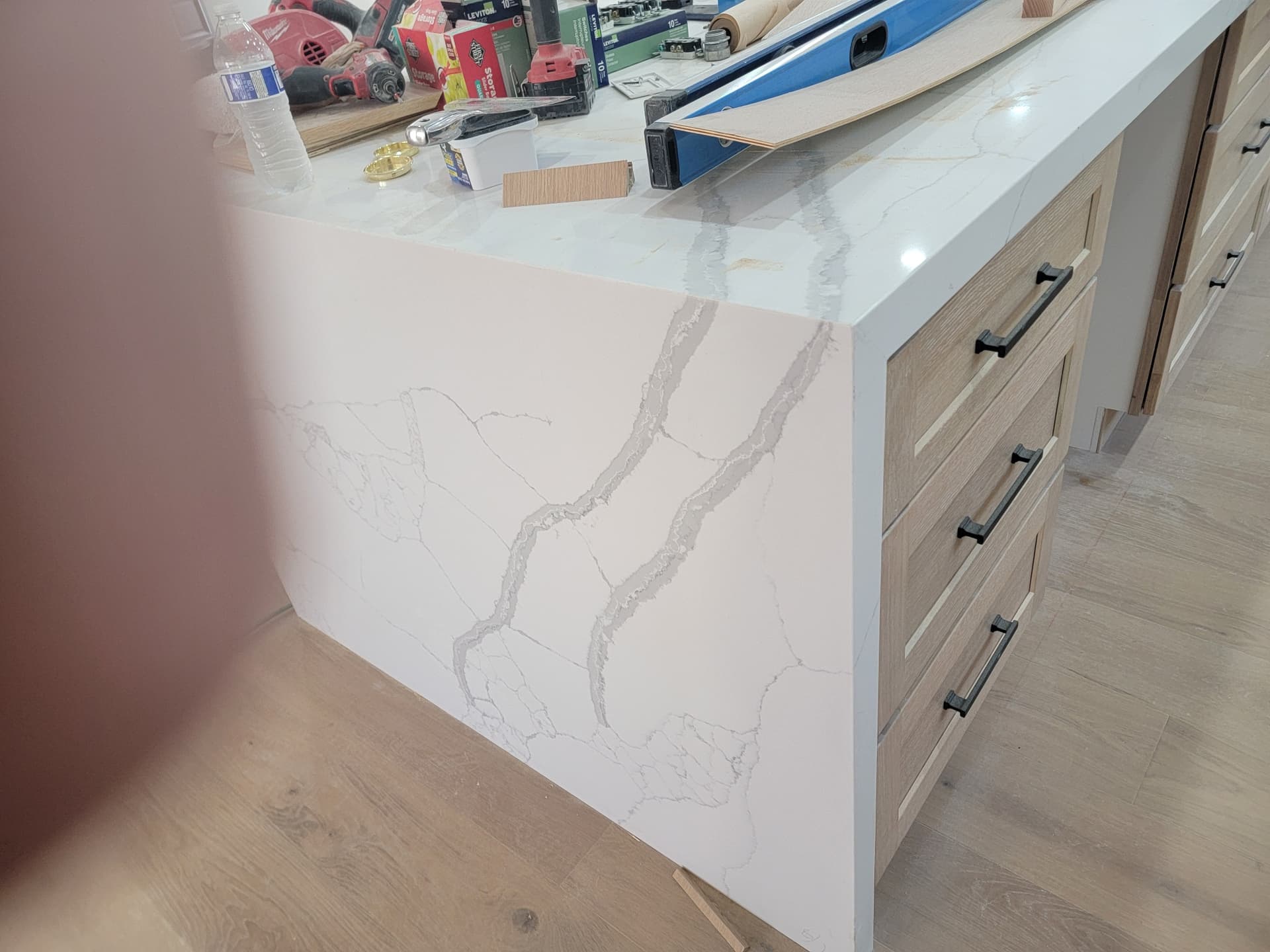 Calacatta quartz kitchen island with full waterfall edge installation and wood shaker cabinet base
